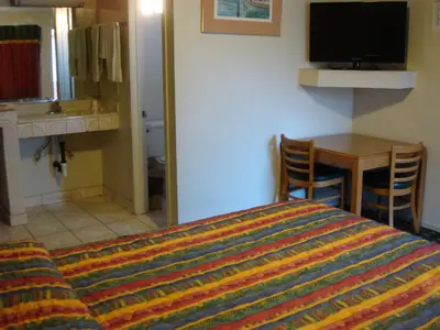 a bedroom with a bed and a table and a television at American Inn in South El Monte