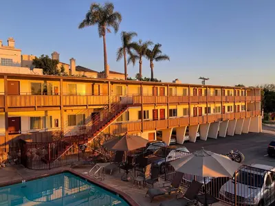 a hotel with a pool and tables and umbrellas at Seahorse Inn Manhattan Beach - LAX in Manhattan Beach