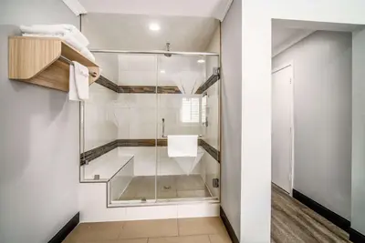 a shower with a glass door in a bathroom at Travelodge Inn & Suites by Wyndham Bell Los Angeles Area in Bell
