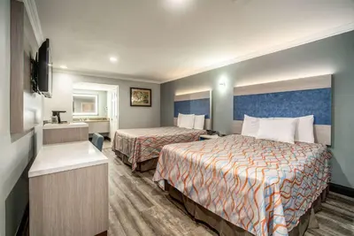 a hotel room with two beds and a television at Travelodge Inn & Suites by Wyndham Bell Los Angeles Area in Bell
