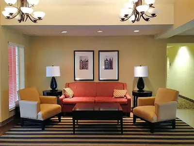a living room with a red couch and two chairs at Extended Stay America Suites - Bakersfield - Chester Lane in Bakersfield