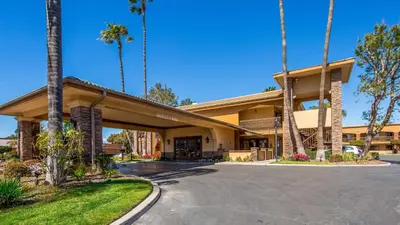 a hotel with palm trees in front of a building at Empire Inn in San Bernardino