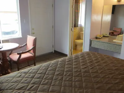 a hotel room with a bed and a table and a bathroom at Park Cienega Motel in Los Angeles