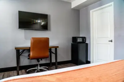 a room with a desk and a television on a wall at LYFE INN & SUITES by AGA - LAX Airport in Inglewood