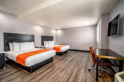 a hotel room with two beds and a desk and a tv at LYFE INN & SUITES by AGA - LAX Airport in Inglewood