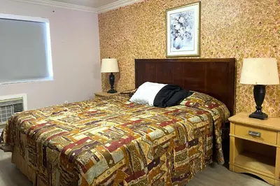 a bedroom with a bed with a colorful blanket and two lamps at Travel Inn Downtown LA in Los Angeles