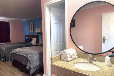 a bathroom with a sink and a mirror next to a bed at Travel Inn Downtown LA in Los Angeles