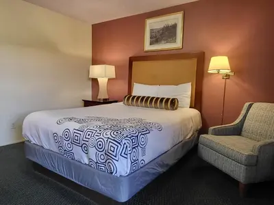 a hotel room with a bed and a chair at Star Inn On Route 66, Barstow in Barstow