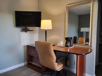 a desk in a hotel room with a chair and a mirror at Star Inn On Route 66, Barstow in Barstow