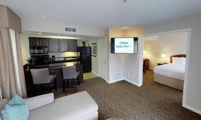 a hotel room with a king bed and a kitchen at Chase Suites Brea-Fullerton - North Orange County in Brea