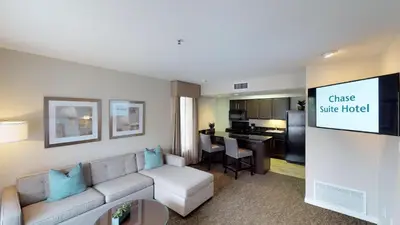 a living room with a couch and a kitchen at Chase Suites Brea-Fullerton - North Orange County in Brea