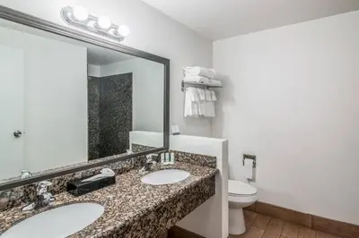 a bathroom with two sinks and a toilet and a mirror at Quality Inn & Suites near Downtown Bakersfield in Bakersfield