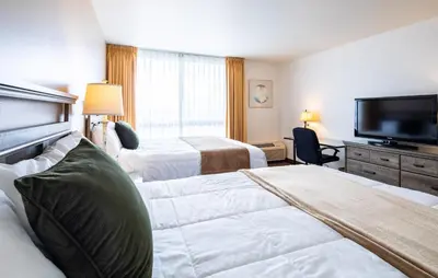 a hotel room with two beds and a flat screen tv at New Gardena Hotel in Gardena