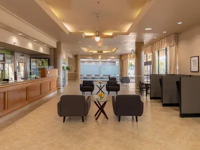 a lobby of a hospital with chairs and a table at New Gardena Hotel in Gardena