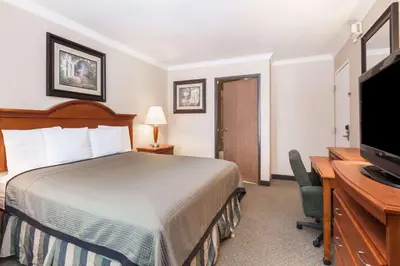 a hotel room with a bed and a desk and a television at Travelodge by Wyndham Sylmar CA in Sylmar