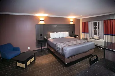a hotel room with a bed and a blue chair at Rodeway Inn & Suites Bellflower in Bellflower