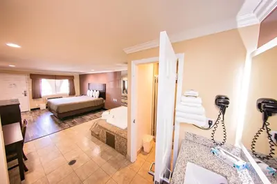 a hotel room with a bed and a bathroom at Rodeway Inn & Suites Bellflower in Bellflower