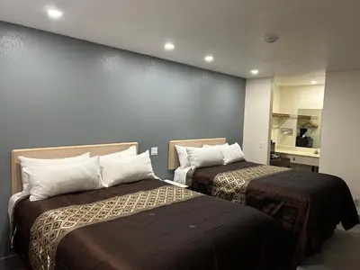 a hotel room with two beds and a wall at California Inn Hotel and Suites Adelanto US 395 in Adelanto