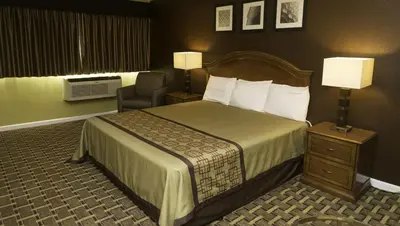 a hotel room with a bed and a chair at Kings Motel Inglewood in Inglewood