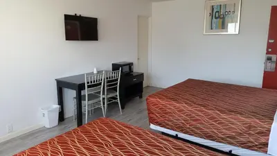 a room with two beds and a desk and a television at Guest Harbor Inn- Port Of Los Angeles San Pedro in San Pedro