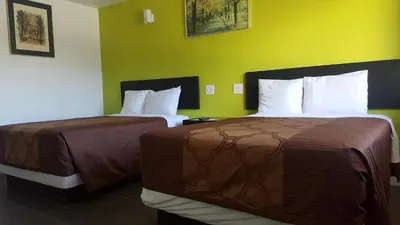 two beds in a hotel room with yellow walls at Guest Harbor Inn- Port Of Los Angeles San Pedro in San Pedro
