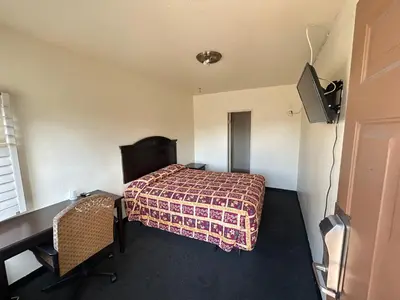 a bedroom with a bed and a desk and a television at Budget Inn Motel in South Gate