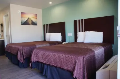 a hotel room with two beds with purple sheets at Beach Inn in Long Beach