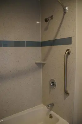 a shower with a glass door next to a tub at Beach Inn in Long Beach