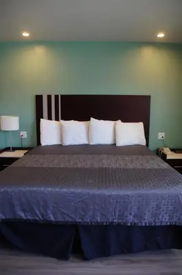 a bedroom with a large bed with a blue comforter at Beach Inn in Long Beach