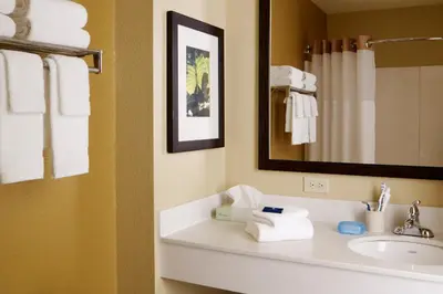 a bathroom with a sink and a mirror and towels at Extended Studio Hotel Suites - Los Angeles - San Dimas in San Dimas