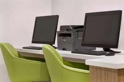 two computer monitors sitting on a desk with green chairs at Wyndham Anaheim in Anaheim