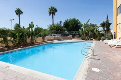 a large blue swimming pool with palm trees at Ramada Plaza by Wyndham Garden Grove/Anaheim South in Anaheim