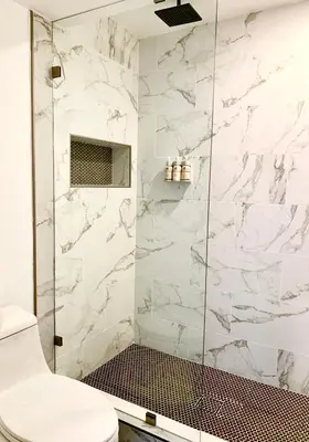 a bathroom with a shower with white marble walls at Sakura Inn in Glendale