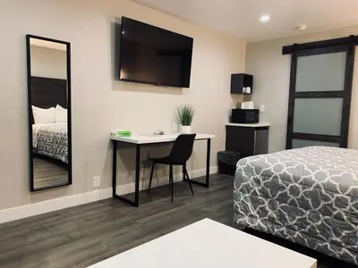 a hotel room with a bed and a desk and a bed and a bed at Sakura Inn in Glendale