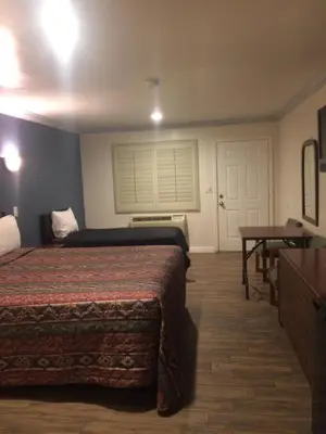 a hotel room with two beds and a table and a window at Royal Inn in Lomita