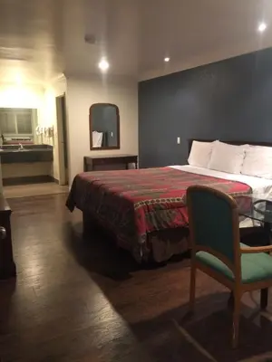 a hotel room with a bed and a chair at Royal Inn in Lomita