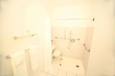 a white bathroom with a shower and a toilet at Travelodge by Wyndham Burbank-Glendale in Burbank