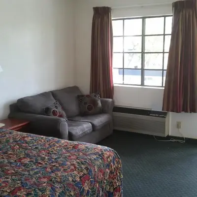 a hotel room with a couch and a bed and a window at Days Inn by Wyndham Orange Anaheim in Orange