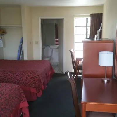 a hotel room with a bed and a desk and a table at Days Inn by Wyndham Orange Anaheim in Orange