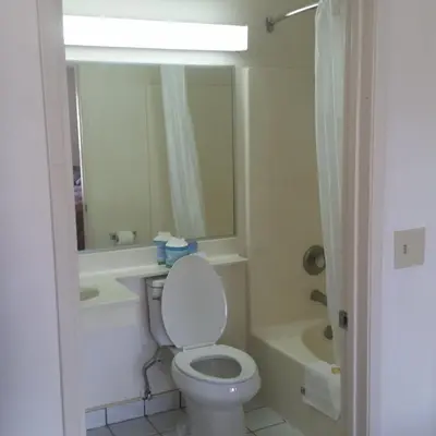a bathroom with a toilet and a sink and a tub at Days Inn by Wyndham Orange Anaheim in Orange