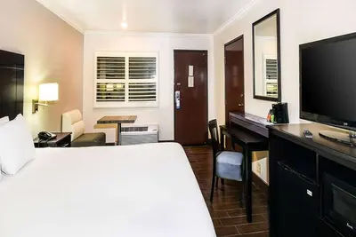 a hotel room with a bed and a desk and a television at Travelodge by Wyndham Commerce Los Angeles Area in Commerce