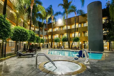 a hotel with a swimming pool in front of a building at Travelodge by Wyndham Commerce Los Angeles Area in Commerce