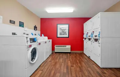 a laundry room with a washing machine and red wall at Extended Stay America Suites - Los Angeles - Torrance Harborgate Way in Carson