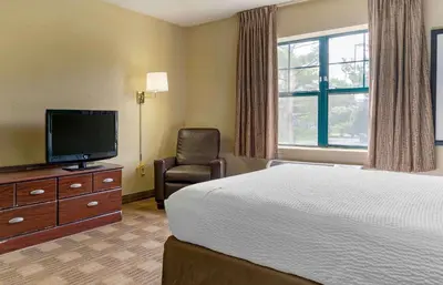 a hotel room with a bed and a tv and a chair at Extended Stay America Suites - Los Angeles - Ontario Airport in Guasti