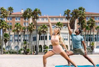 a man and a woman doing yoga on the beach at Casa Del Mar in Los Angeles