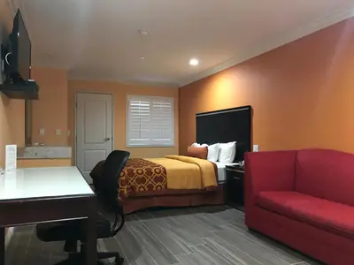 a hotel room with a bed and a red couch at Executive Suites Inn in Westminster
