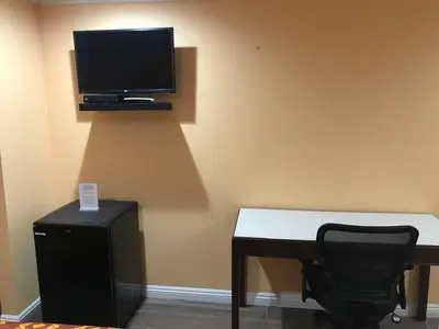 a room with a desk and a tv on the wall at Executive Suites Inn in Westminster