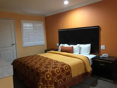 a hotel room with a bed with a large headboard at Executive Suites Inn in Westminster