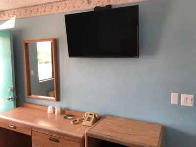 a room with a television on a wall with a table at Chester Inn Motel in Stanton