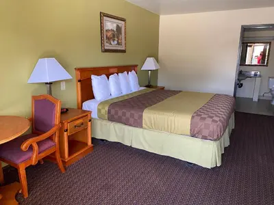 a hotel room with a bed and a table and a chair at Chariot Inn Glendale - Pasadena in Glendale